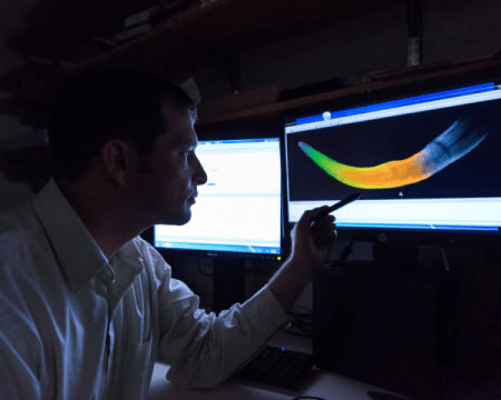 미시건 대학의 박사과정 학생인 마이클 처니가 색을 입힌 어린 털매머드 엄니의 CT 스캔 이미지를 보여주고 있다. 서로 다른 색깔은 성장연도를 나타낸다. Credit: Image courtesy of University of Michigan